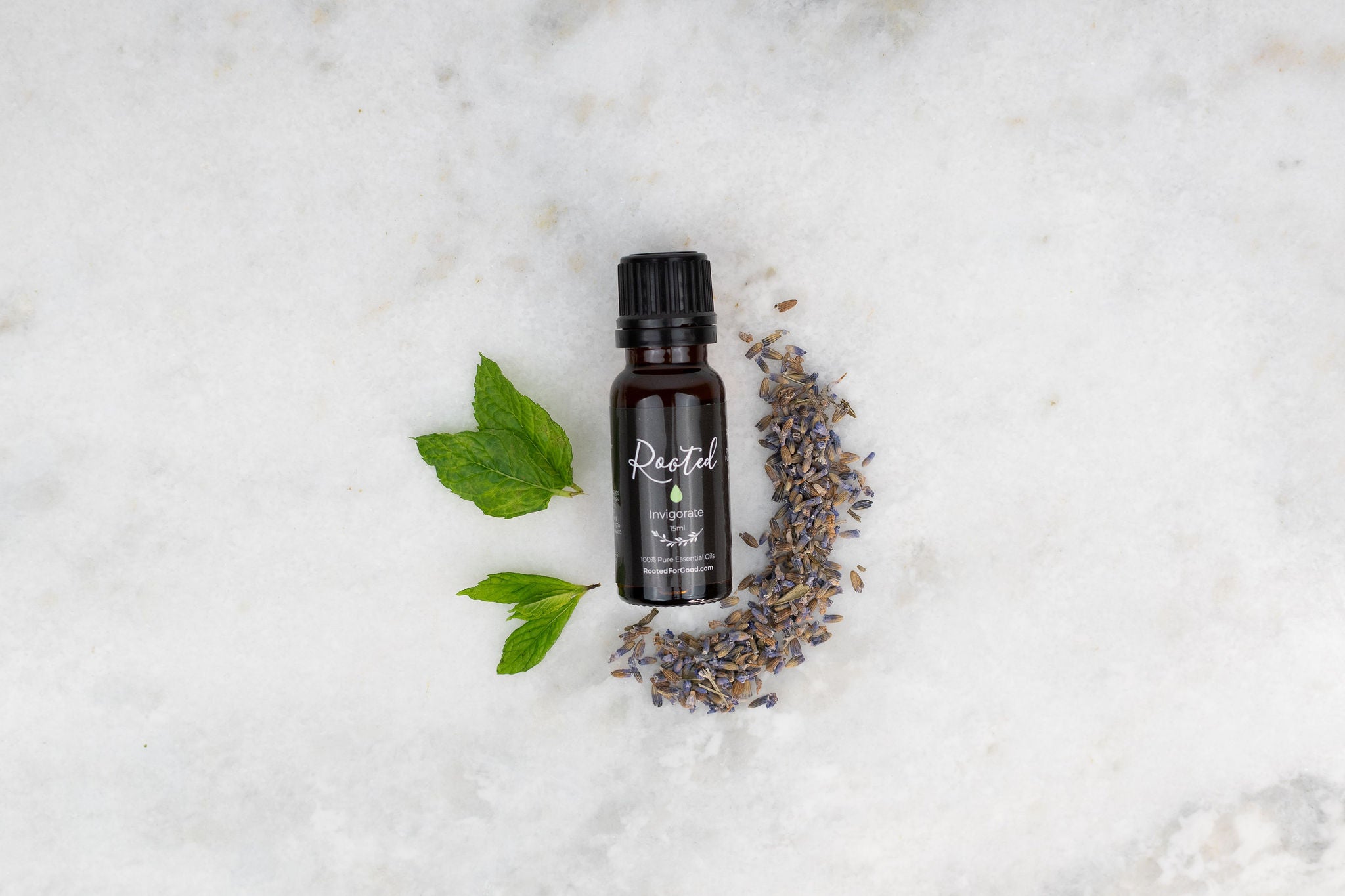 Invigorate essential oil bottle with fresh citrus and mint leaves arranged on a wooden surface in a flat lay style
