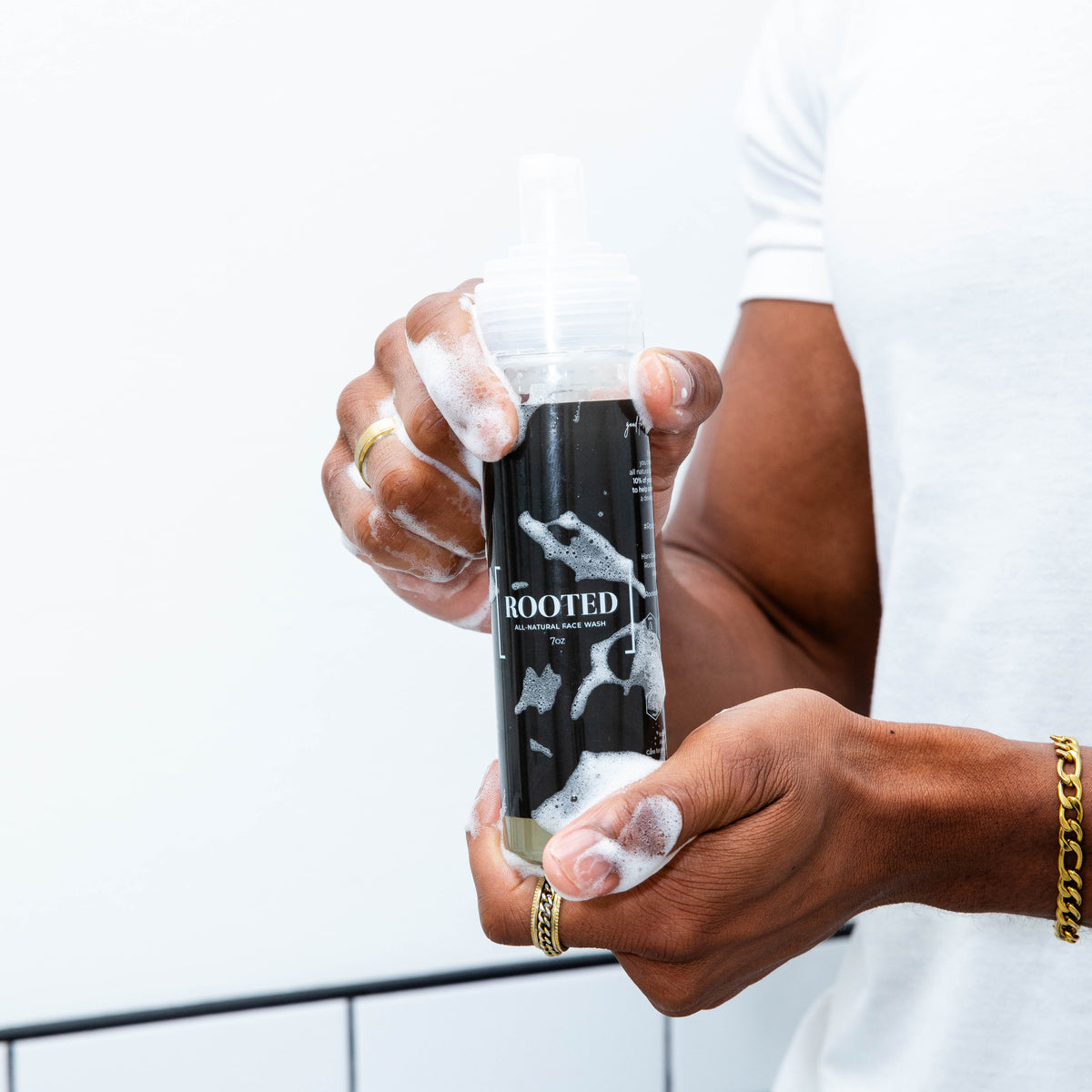 Man holding bottle of natural face wash with a black and while label 